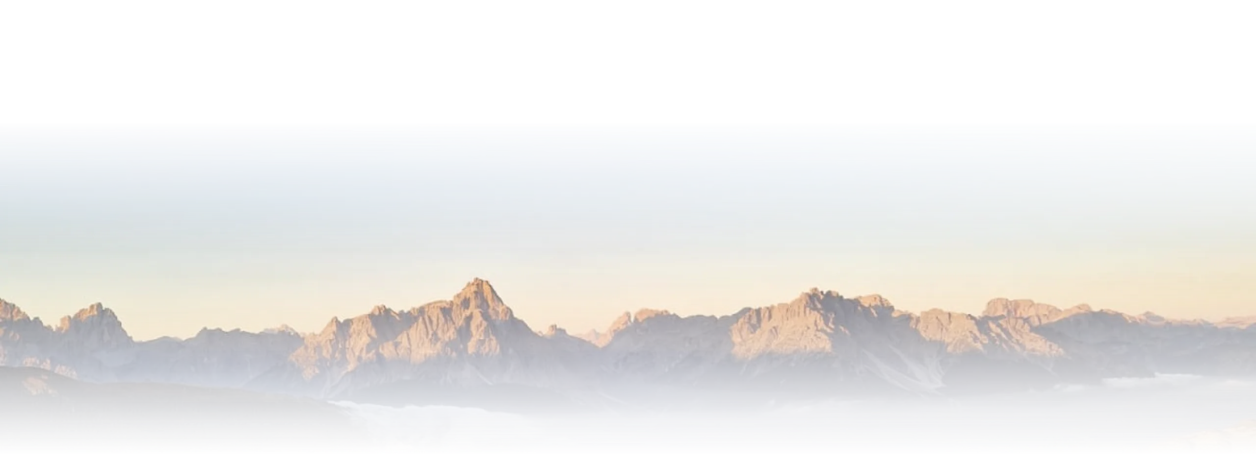 Alpenpanorama mit Felsgipfeln im warmen Morgenlicht über Wolken